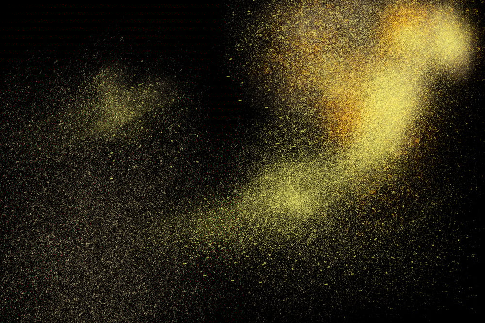 Freeze motion of yellow powder exploding, isolated on black, dark background. Abstract design of yellow dust cloud. Particles explosion screen saver, wallpaper. Freeze motion of yellow powder exploding, isolated on black, dark background. Abstract design of yellow dust cloud. Particles explosion screen saver, wallpaper.